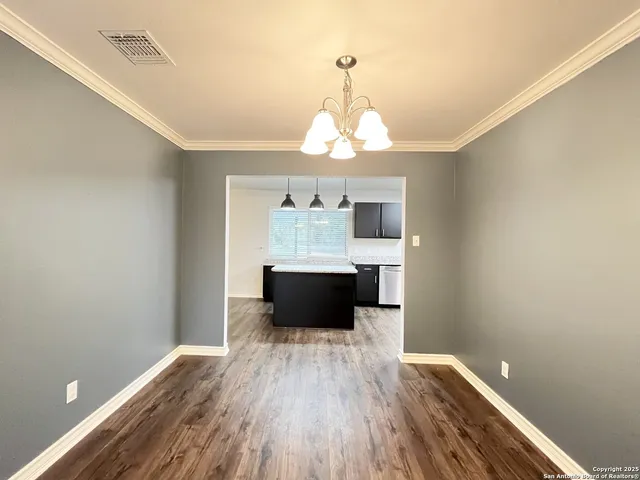 a living room with wooden floor and chandelier