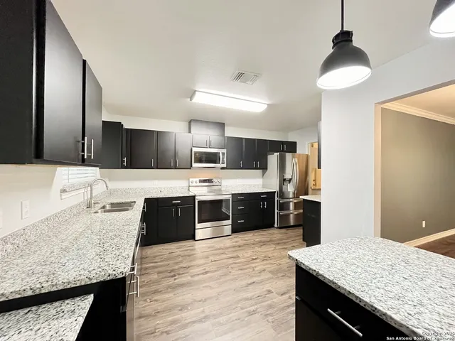 a large kitchen with granite countertop a sink counter space and cabinets