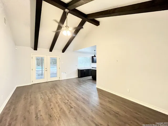 a view of a big room with wooden floor and windows