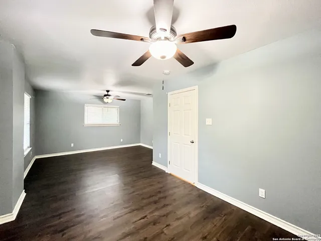 a view of an empty room with a ceiling fan and wooden floor
