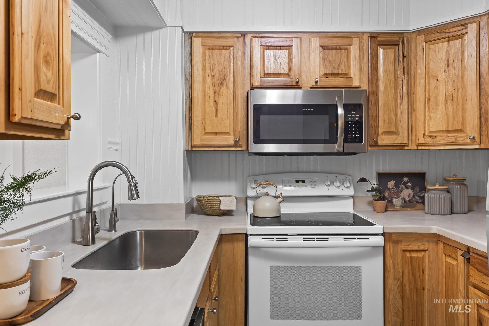7514 West Swift Lane Boise, ID 83704 - Photo 12 of 46 Kitchen featuring white electric stove, light countertops, stainless steel microwave, and brown cabinetry