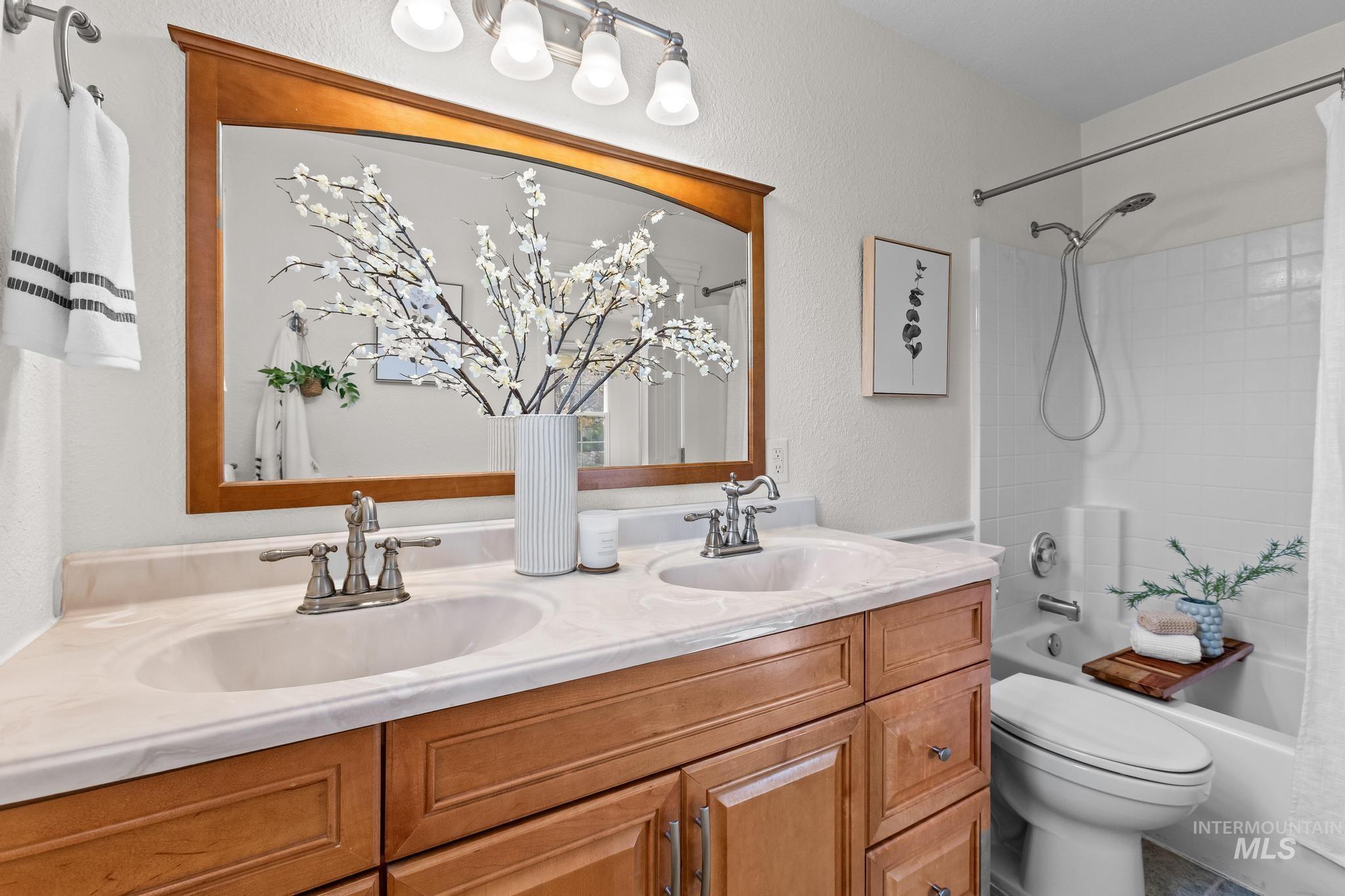 7514 West Swift Lane Boise, ID 83704 - Photo 18 of 46 Bathroom with shower / bathtub combination with curtain, double vanity, and a textured wall