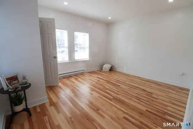 a view of empty room with wooden floor and fan