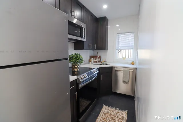 a kitchen with a sink cabinets stainless steel appliances and a window