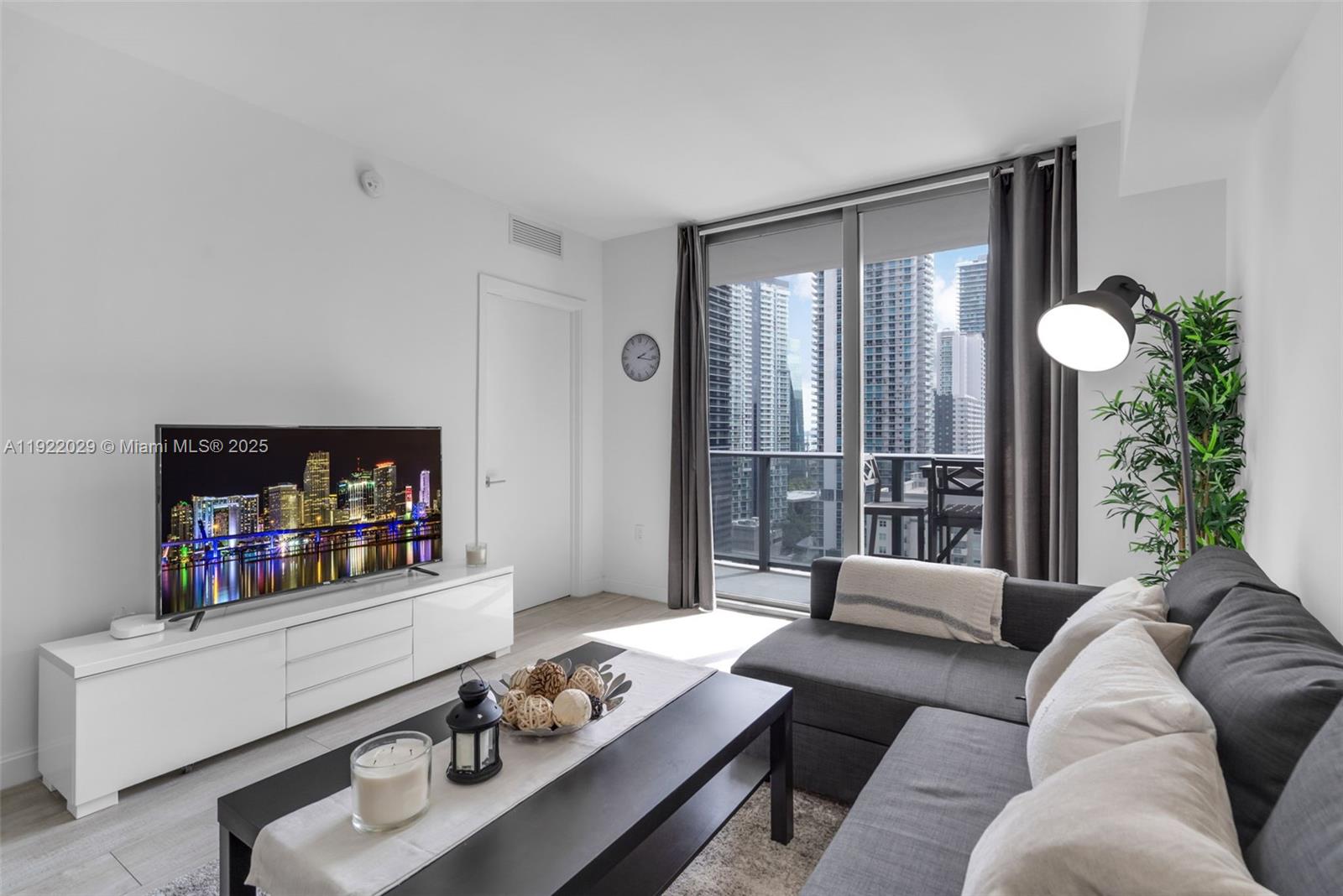 55 Southwest 9th Street, Unit 1705 Miami, FL 33130 - Photo 5 of 28 a living room with furniture and a book shelf
