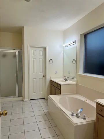 a spacious bathroom with a tub a sink and a mirror