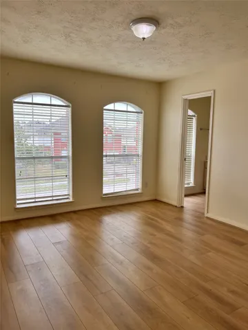 an empty room with wooden floor and windows