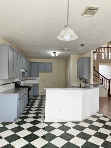a large kitchen with a white checkered floor and a chandelier