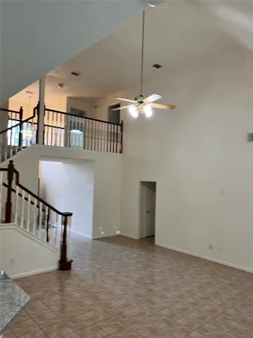 a view of an empty room with chandelier fan