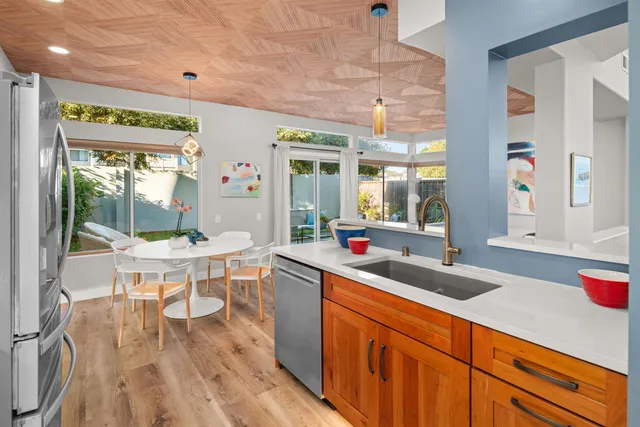 a kitchen with stainless steel appliances granite countertop a refrigerator a stove a sink dishwasher a dining table and chairs with wooden floor