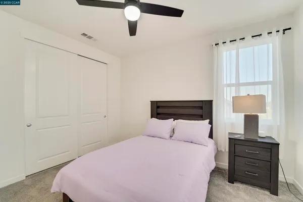 a bedroom with a large bed and a chandelier fan