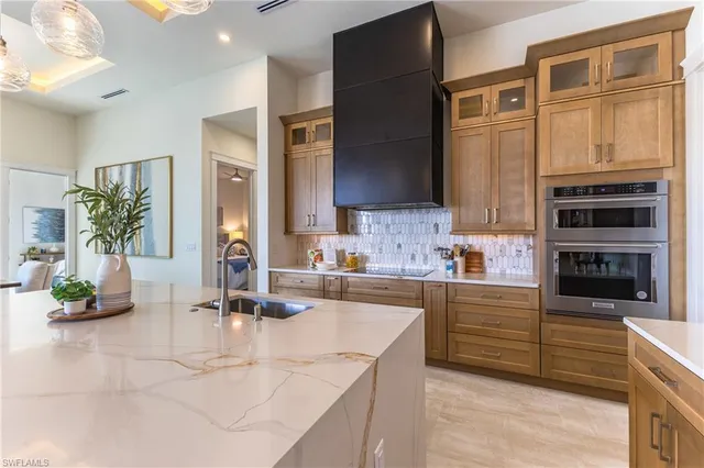 a kitchen with stainless steel appliances kitchen island granite countertop a refrigerator a stove and a sink