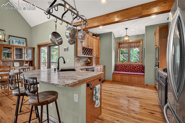 255 Summit Road Manitou Springs, CO 80829 - Photo 13 of 48 Open concept kitchen with leathered granite countertops, pullout pantry shelves, custom knotty hickory cabinetry, window seat with storage, knotty pecan flooring, breakfast bar seating and custom painted aspen tiles!