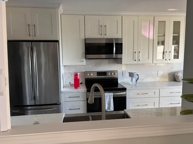 a kitchen with stainless steel appliances granite countertop a refrigerator stove and white cabinets