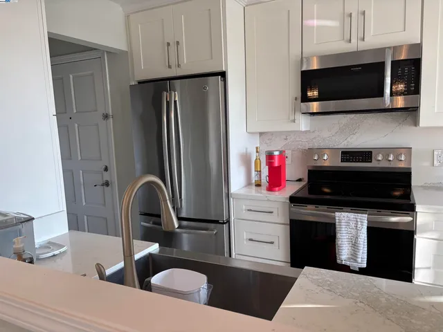 a kitchen with stainless steel appliances granite countertop a stove top oven microwave and refrigerator