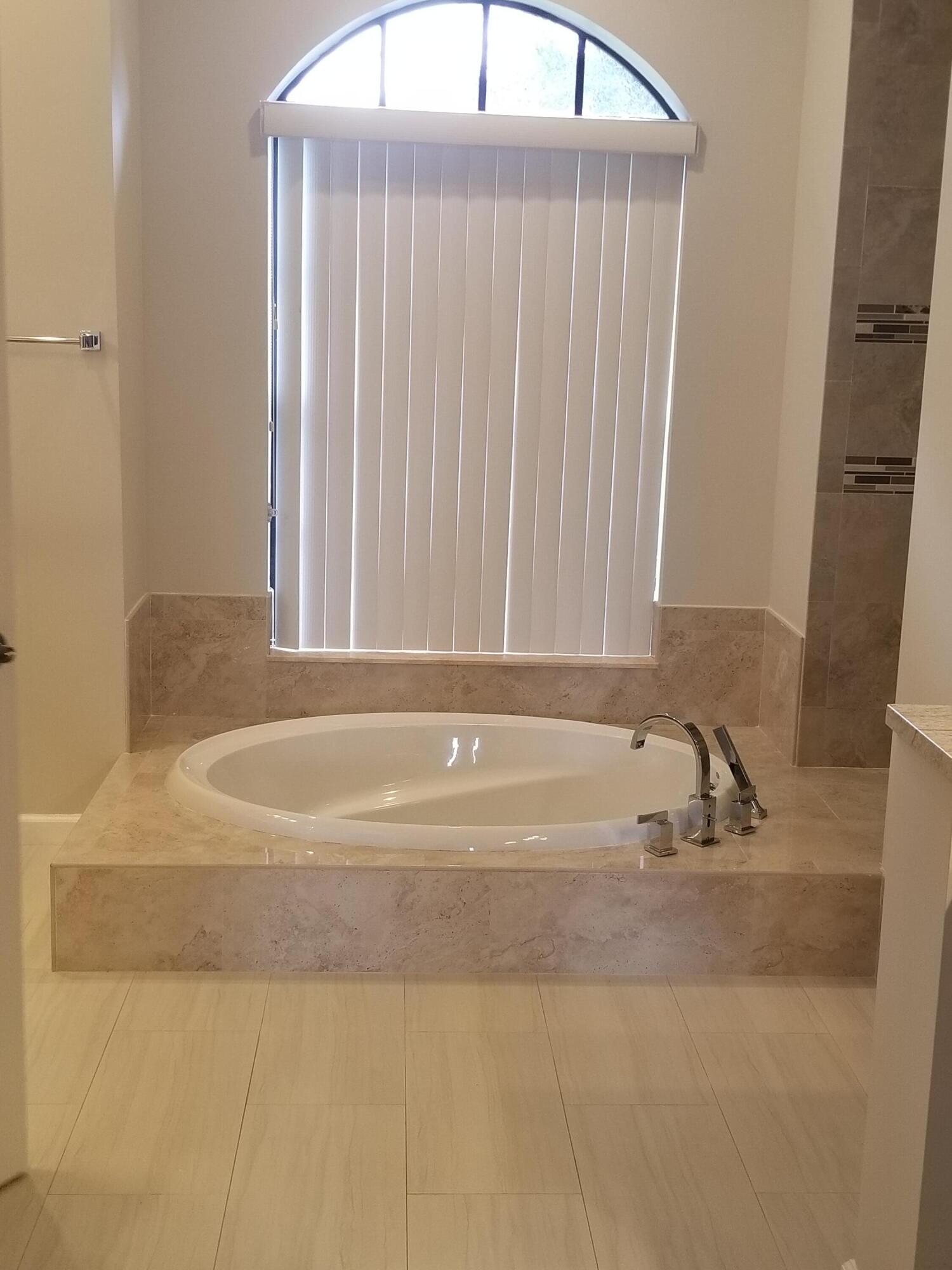 8709 Man O War Road Palm Beach Gardens, FL 33418 - Photo 15 of 27 a bathroom with a bathtub and a sink