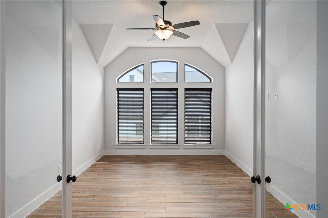 412 Pin Cherry Pass San Marcos, TX 78666 - Photo 11 of 27 an empty room with wooden floor chandelier fan and windows