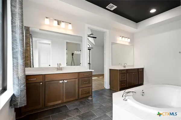 a spacious bathroom with a tub sink and mirror