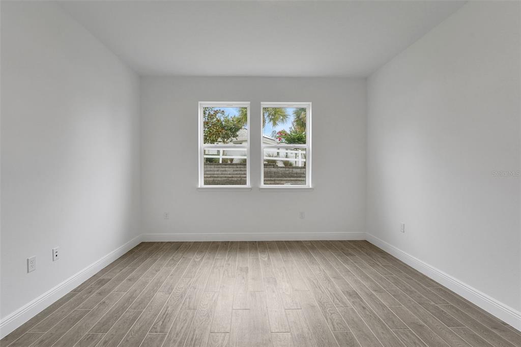 987 Fiesta Key Circle Lady Lake, FL 32159 - Photo 17 of 39 an empty room with wooden floor and windows