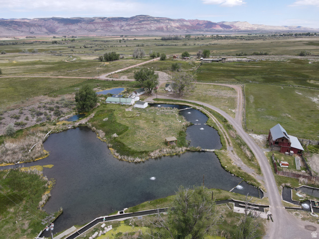 Expansive property featuring multiple ponds with water aeration, a red barn with a metal roof, a white outbuilding, and a gravel road network
