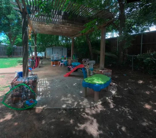 a view of a backyard with table and chairs potted plants and large tree