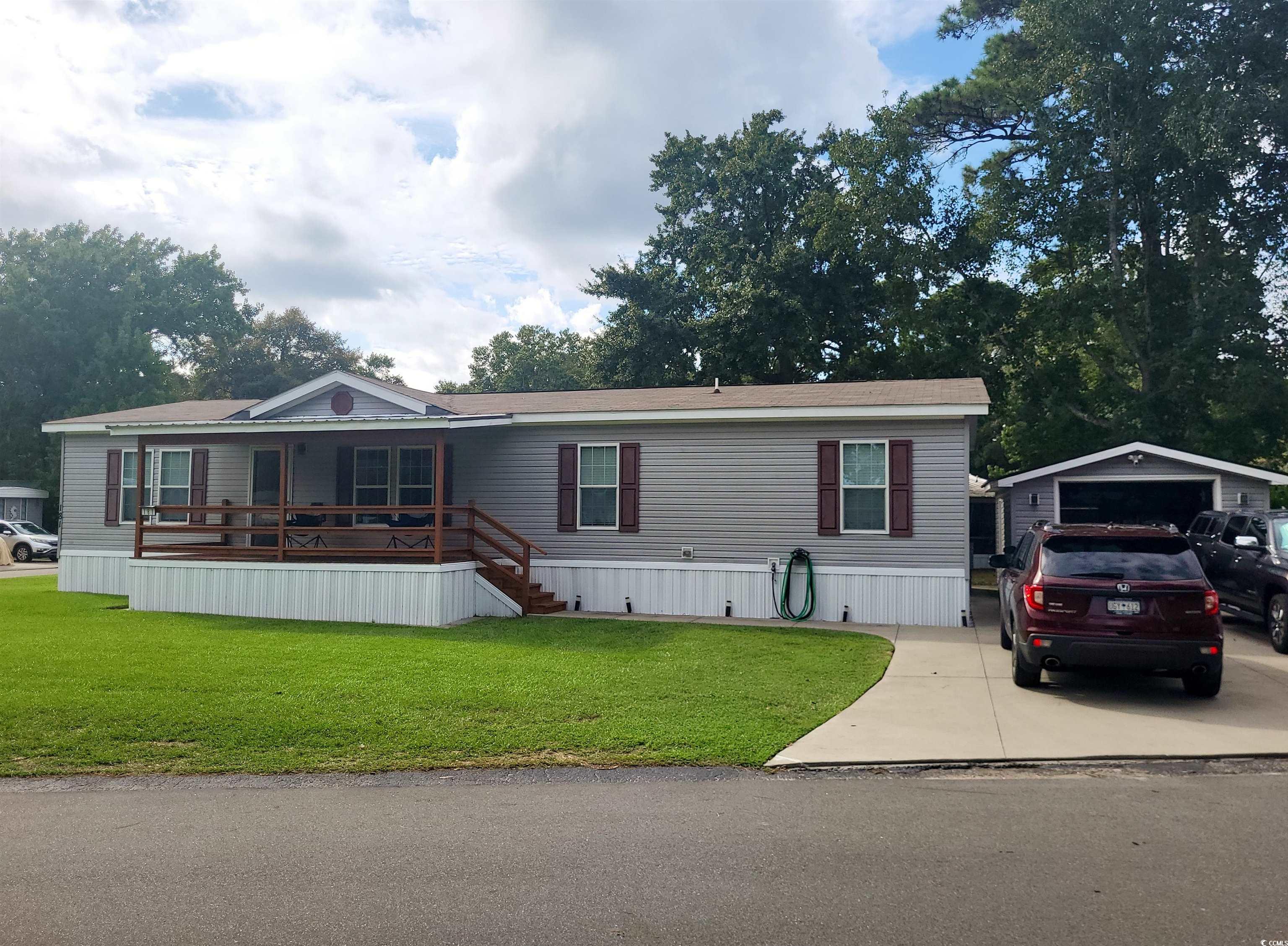 Manufactured home featuring a garage, front lawn, covered porch, and concrete driveway.