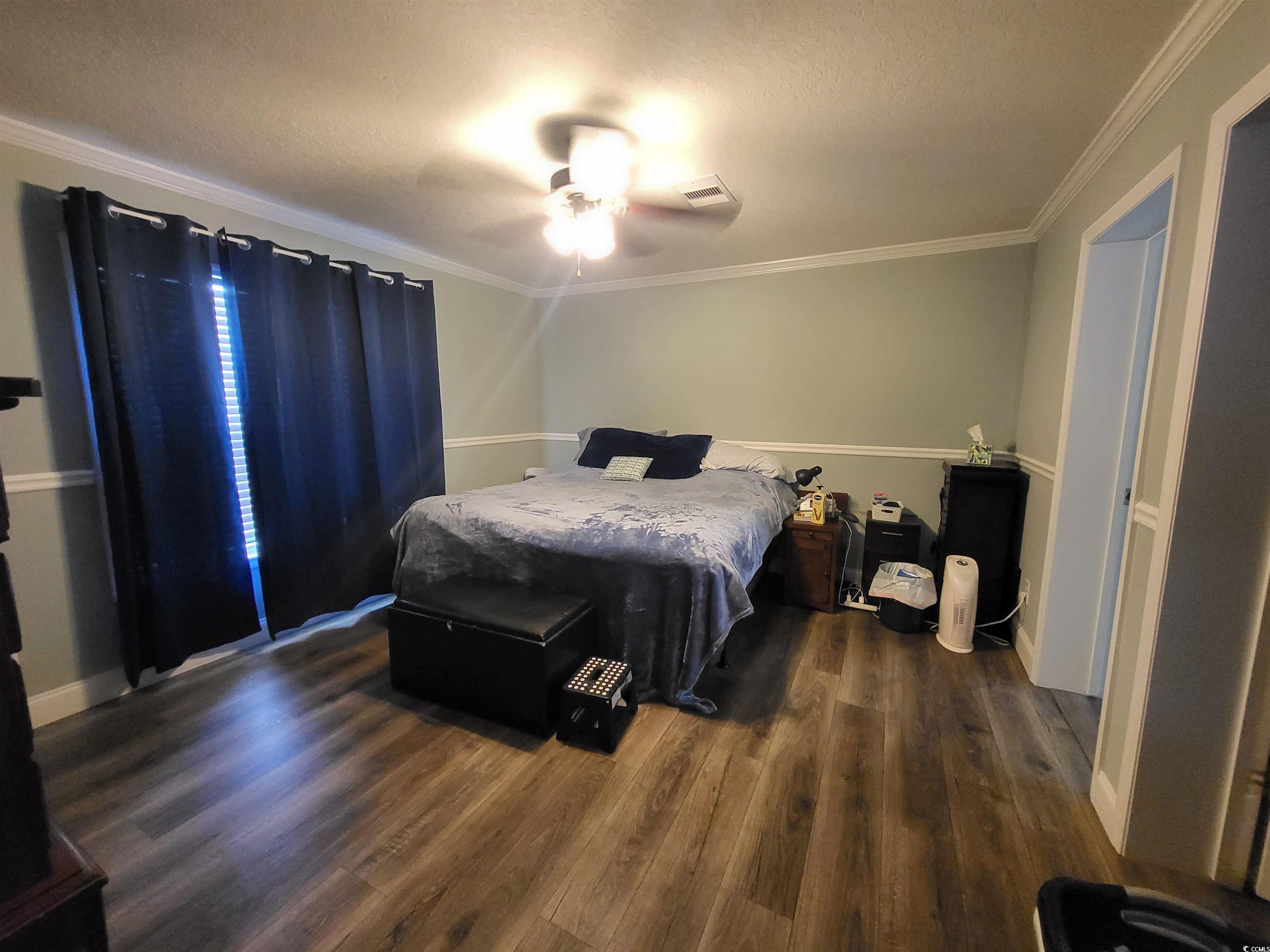 181 Offshore Drive Murrells Inlet, SC 29576 - Photo 11 of 28 Bedroom featuring ceiling fan, crown molding, dark wood-style floors, and a textured ceiling