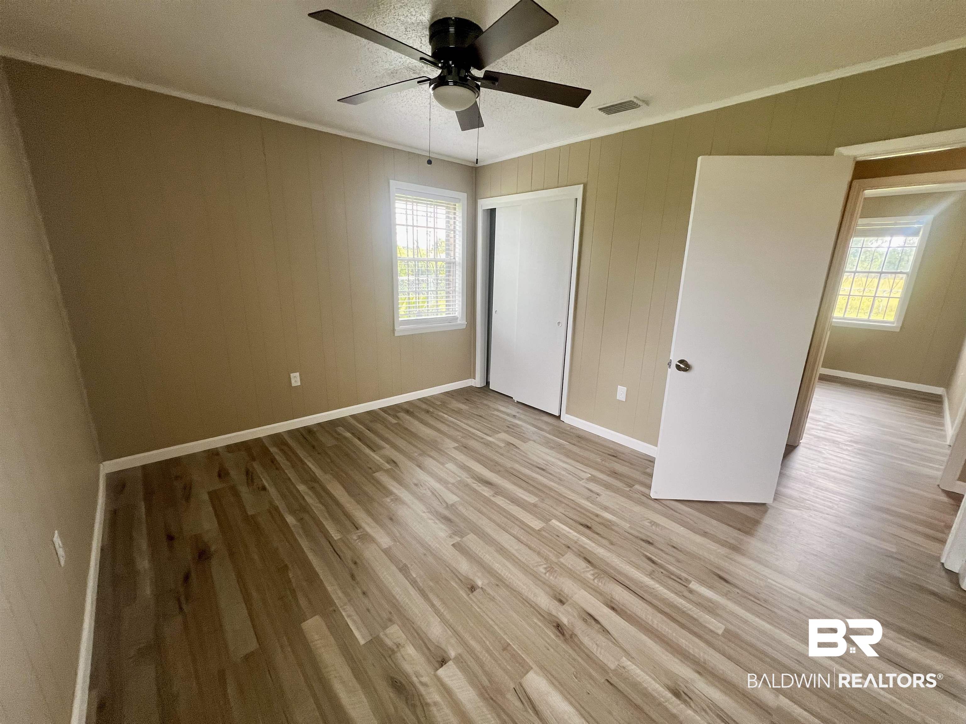 508 Freemanville Drive Atmore, AL 36502 - Photo 15 of 27 Unfurnished bedroom featuring light hardwood / wood-style floors, multiple windows, and ceiling fan