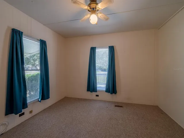 an empty room with ceiling fan and window