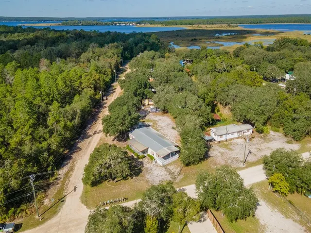 an aerial view of residential house with outdoor space and trees all around