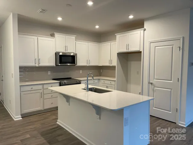 a kitchen with kitchen island a sink stainless steel appliances and cabinets
