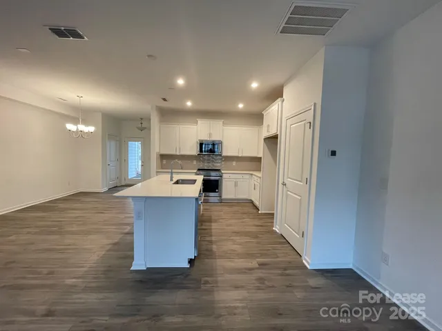 a kitchen with stainless steel appliances granite countertop a refrigerator a sink dishwasher and a oven with wooden floor