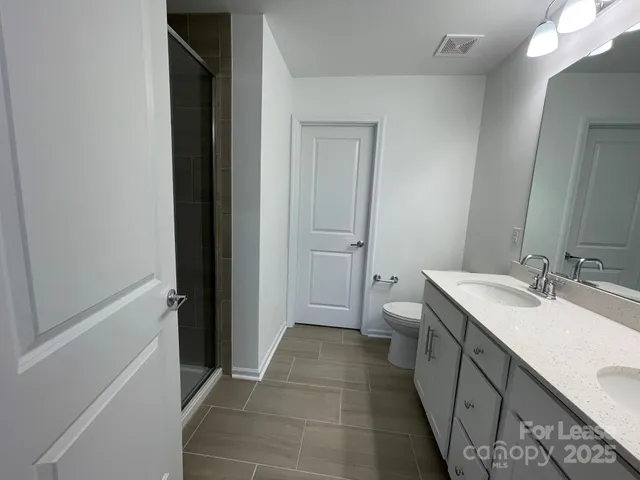a bathroom with a double vanity sink toilet and shower