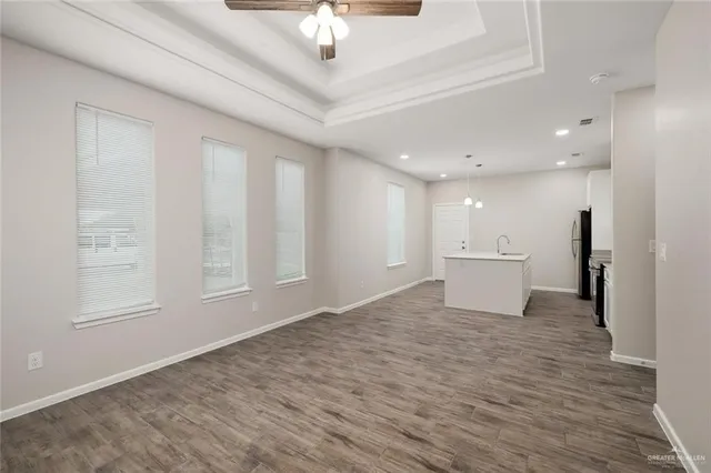 a view of a livingroom with a chandelier fan and wooden floor