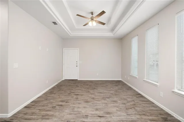 an empty room with wooden floor and ceiling fan