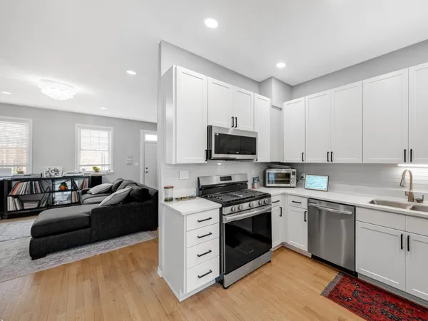 a kitchen with stainless steel appliances a stove a sink a refrigerator and white cabinets