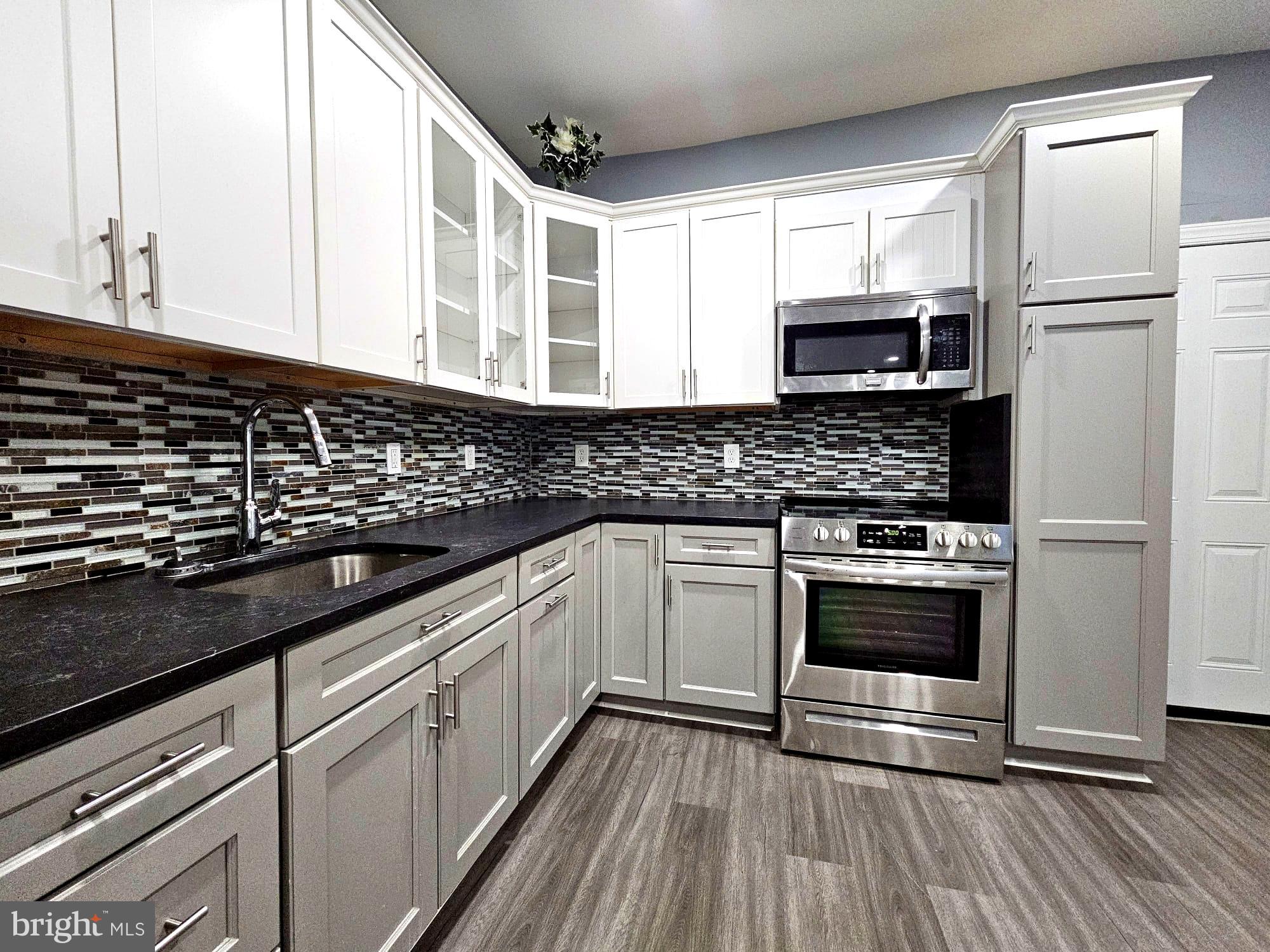 827 South 56th Street Philadelphia, PA 19143 - Photo 11 of 36 a kitchen with stainless steel appliances a sink dishwasher a stove microwave and refrigerator