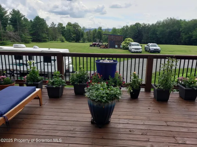 a view of a balcony with chairs potted plants and wooden floor