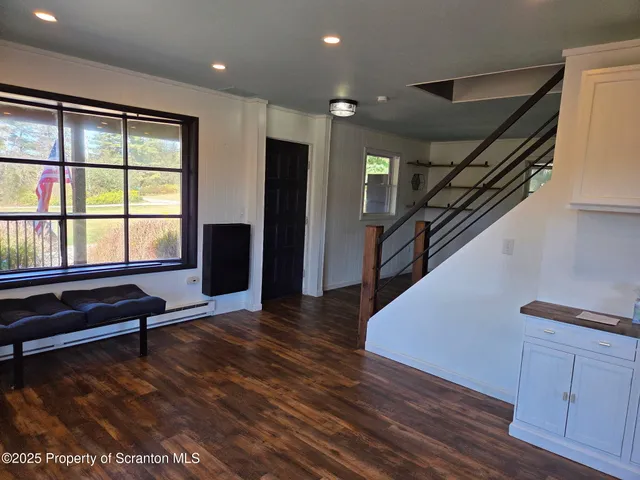 a view of an empty room with wooden floor and stairs