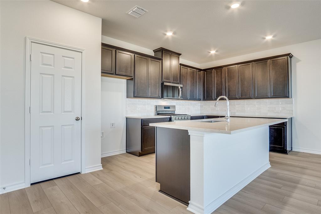 329 Fallbrook Drive Aledo, TX 76008 - Photo 11 of 33 a kitchen with kitchen island granite countertop wooden cabinets a sink and stainless steel appliances