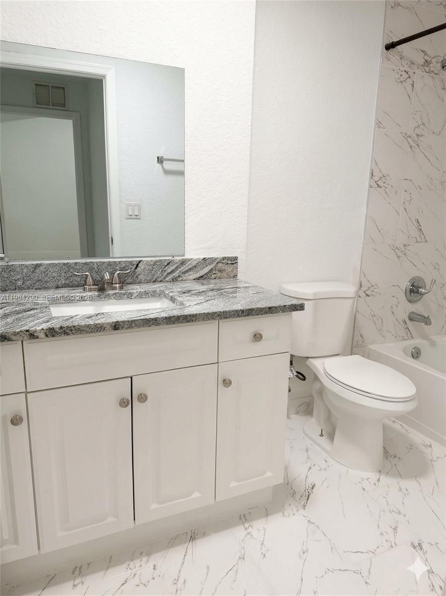 2801 Riverside Drive, Unit 204 Coral Springs, FL 33065 - Photo 7 of 20 a bathroom with a granite countertop toilet sink and mirror