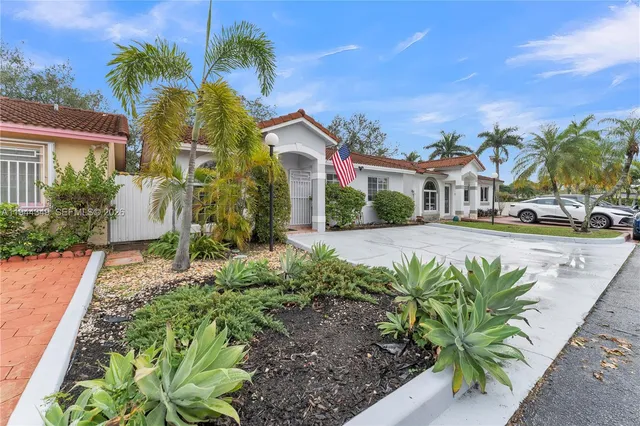 a front view of a house with a yard and potted plants