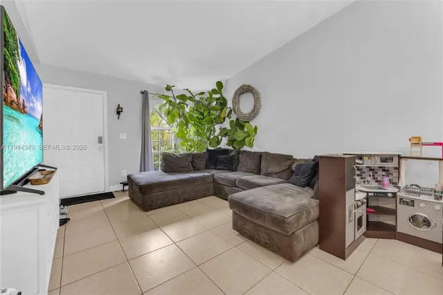 a living room with furniture a flat screen tv and a window