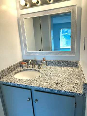 a bathroom with a granite countertop sink and a mirror