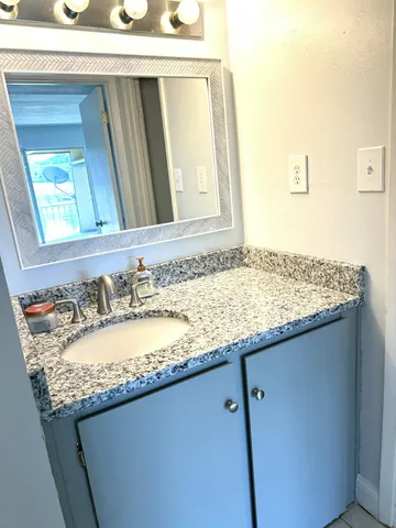 a bathroom with a granite countertop sink and a mirror