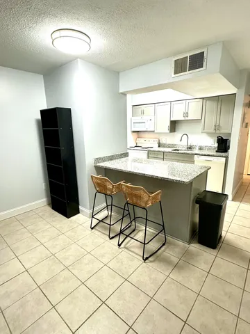 a kitchen with stainless steel appliances kitchen island granite countertop a sink and a refrigerator