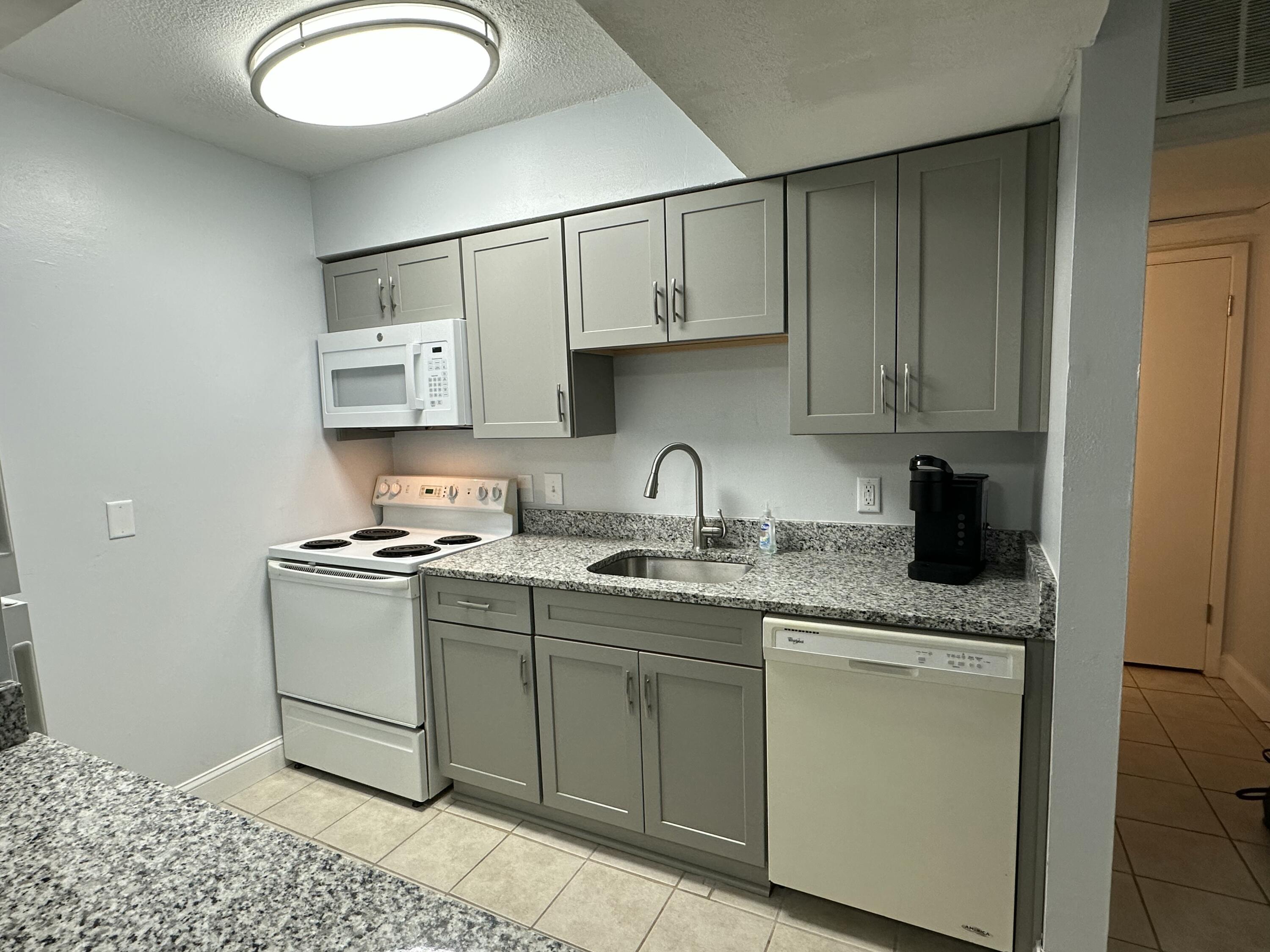 210 Pelham Road, Unit 208C Fort Walton Beach, FL 32547 - Photo 5 of 13 a kitchen with stainless steel appliances granite countertop a sink stove and cabinets