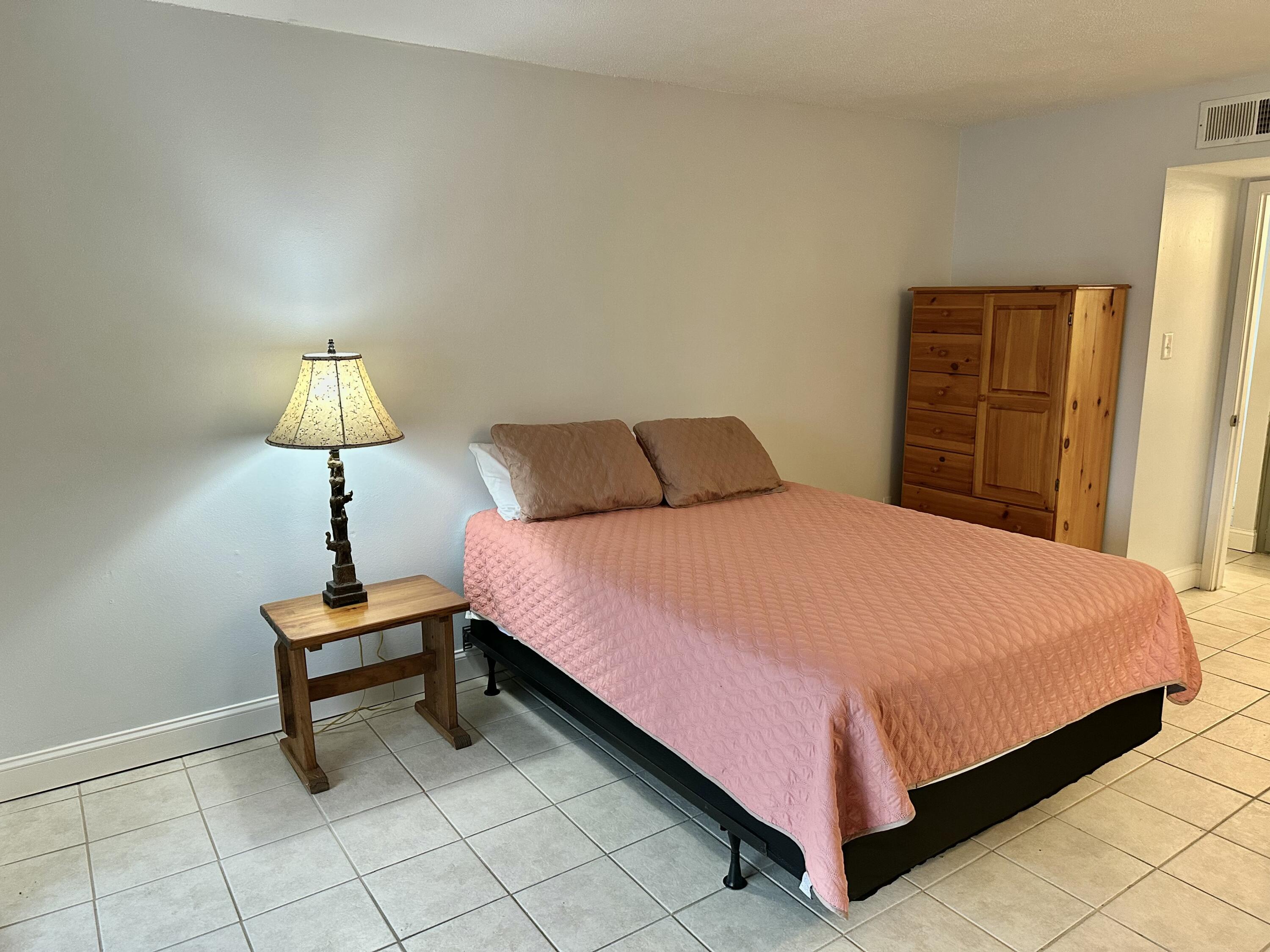 210 Pelham Road, Unit 208C Fort Walton Beach, FL 32547 - Photo 7 of 13 a bedroom with a bed and a lamp