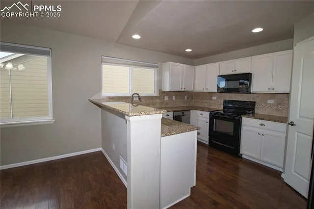 a kitchen with granite countertop white cabinets sink and stainless steel appliances
