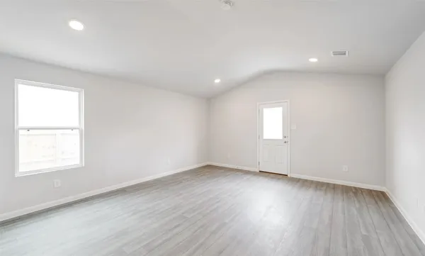 an empty room with wooden floor and windows